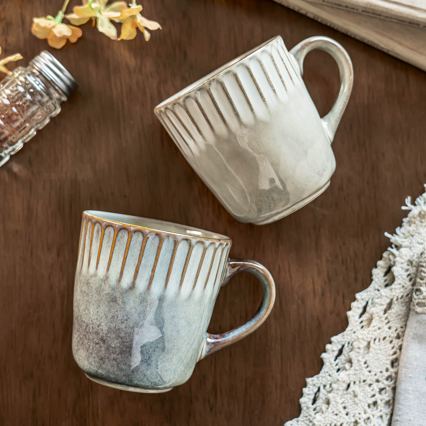 Pair of reactive glaze ceramic mugs on wooden table