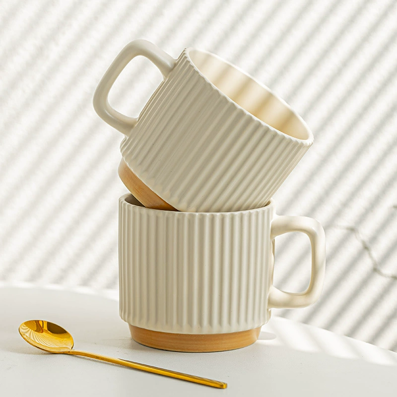 Two ribbed ceramic mugs stacked with a gold color spoon